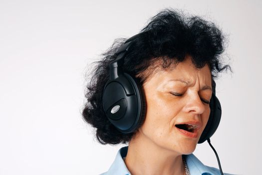 Close-up portrait of a singing elder woman with headphones.