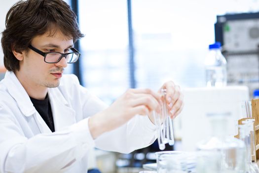 young, male researcher/chemistry student carrying out scientific research in a lab (shallow DOF; color toned image)