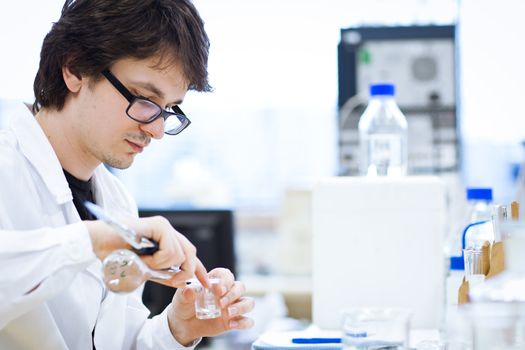 young, male researcher/chemistry student carrying out scientific research in a lab (shallow DOF; color toned image)