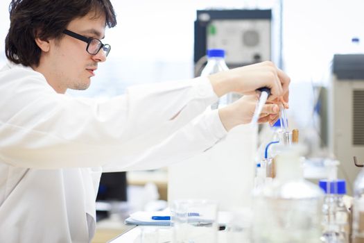 young, male researcher/chemistry student carrying out scientific research in a lab (shallow DOF; color toned image)