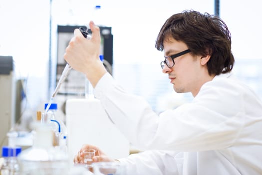 young, male researcher/chemistry student carrying out scientific research in a lab (shallow DOF; color toned image)