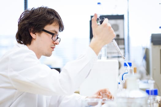 young, male researcher/chemistry student carrying out scientific research in a lab (shallow DOF; color toned image)