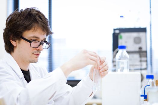 young, male researcher/chemistry student carrying out scientific research in a lab (shallow DOF; color toned image)