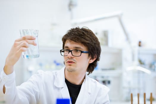 young, male researcher/chemistry student carrying out scientific research in a lab (shallow DOF; color toned image)