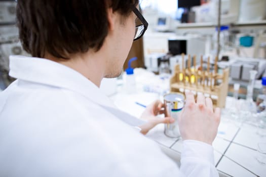 young, male researcher/chemistry student carrying out scientific research in a lab (shallow DOF; color toned image)