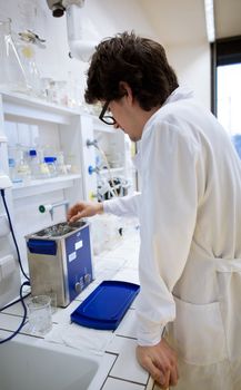 young, male researcher/chemistry student carrying out scientific research in a lab (shallow DOF; color toned image)