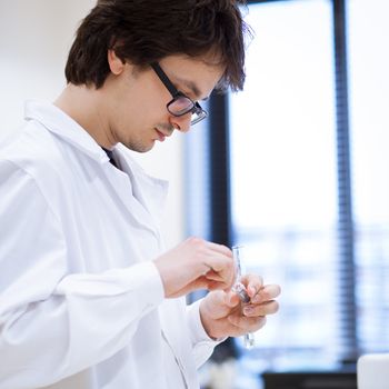 young, male researcher/chemistry student carrying out scientific research in a lab (shallow DOF; color toned image)