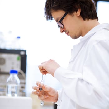 young, male researcher/chemistry student carrying out scientific research in a lab (shallow DOF; color toned image)