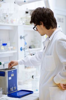 young, male researcher/chemistry student carrying out scientific research in a lab (shallow DOF; color toned image)