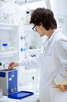 young, male researcher/chemistry student carrying out scientific research in a lab (shallow DOF; color toned image)