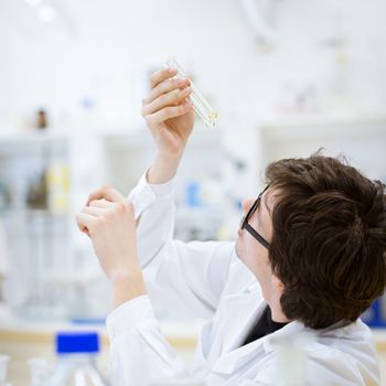 young, male researcher/chemistry student carrying out scientific research in a lab (shallow DOF; color toned image)