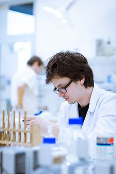 young, male researcher/chemistry student carrying out scientific research in a lab (shallow DOF; color toned image)