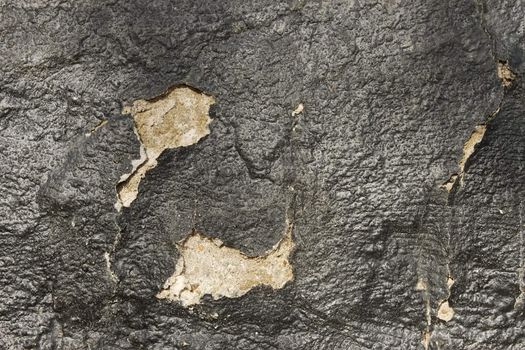 Fragment of old wall with a shelled hydrophobic coating of black pitch