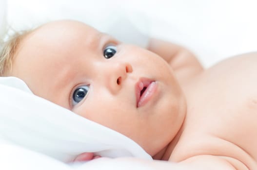 Beautiful cute baby girl is lying in a bed.