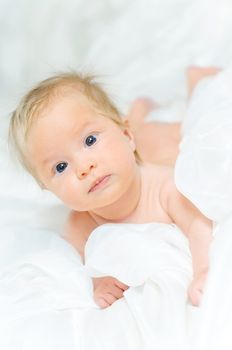 Beautiful cute baby girl is lying in a bed.