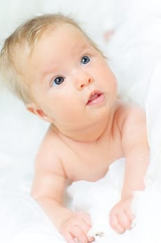 Beautiful cute baby girl is lying in a bed.