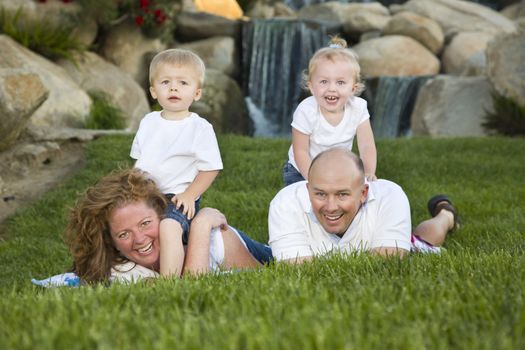 Happy Young Adorable Family with Twins Portrait on Grass in the Park.