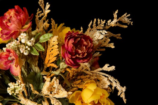 A low key photograph of a bunch of artificial flowers on a black background