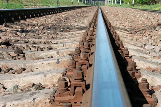 Railway rail that goes afield. Blue sky reflected in a sleek metal