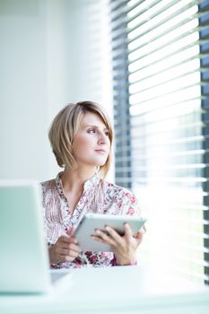 Pretty college student/businesswoman working on her tablet computer (shallow DOF; color toned image)