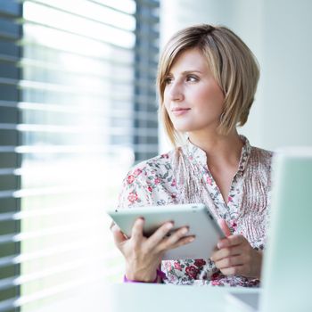 Pretty college student/businesswoman working on her tablet computer (shallow DOF; color toned image)