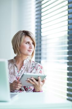 Pretty college student/businesswoman working on her tablet computer (shallow DOF; color toned image)