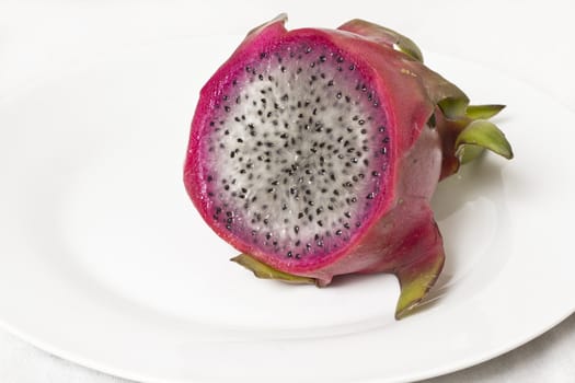 A juicy dragon fruit cut into half over a white background