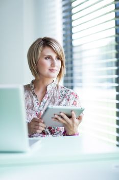 Pretty college student/businesswoman working on her tablet computer (shallow DOF; color toned image)