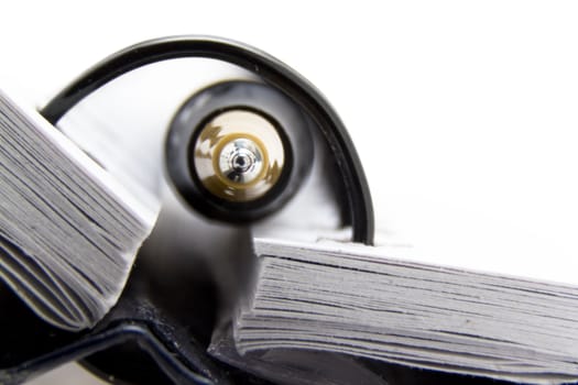 a closeup shot of a pen sticking out through a spiral ring binder of a notebook