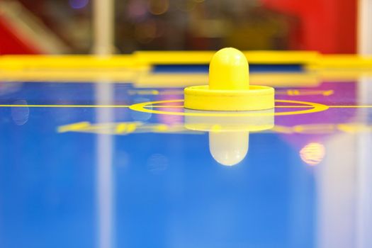 Yellow air hockey mallet on a blue an air-hockey table