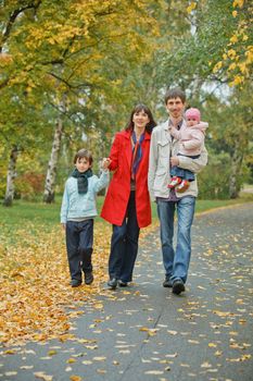 Happy family in park. Father, mother with daughter and son walking in the autumn park. Vertical view