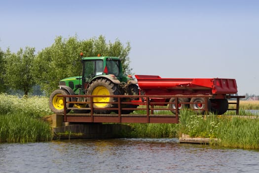 Tractor at work driving on country road and over bridge