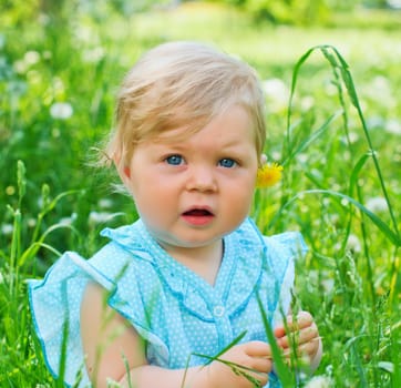 Clouse-up portrait pretty little girl sitting in the grass in the park