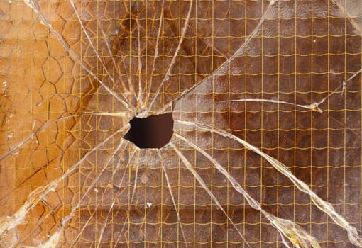 Close up of a broken reinforced glass  cracked with hole 