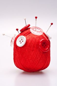 red and white pins in red wool ball with buttons
