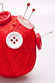 red and white pins in red wool ball with buttons