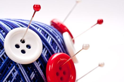 red and white pins in red wool ball with buttons