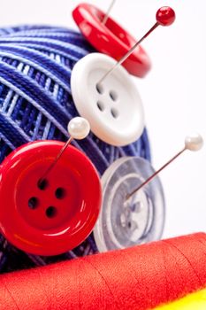 red and white pins in wool ball with buttons