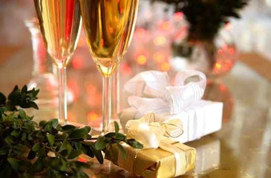 Champagne in glasses, green twig and gift boxes.