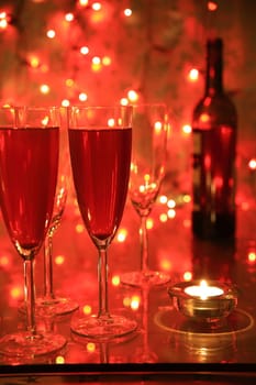 Champagne in glasses, candlelights and blured lights on red background