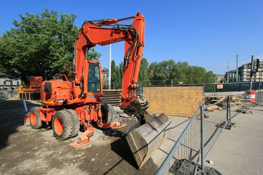 Big red digger standing in a construction site in the city