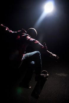 A skateboarder performs tricks under dramatic rim lighting with lens flare. Shallow depth of field.