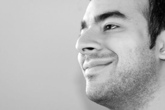 Black and white portrait of a young man smiling - plenty of copy space to the left.