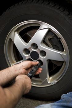 Close-up detail of a mechanic tightening or lossening the lugs of an aluminum rim.