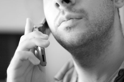 Black and white portrait of an unshaven young man talking on his celly phone.
