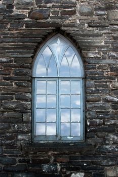 an old castle star shaped window against a stone wall with a cloud background