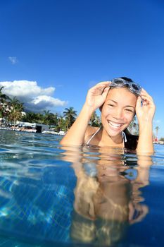 Pool woman on holidays in tropical resort swimming. Beautiful girl smiling with goggles. Asian Caucasian young woman model.