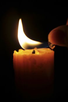 hand lighting candle in the dark