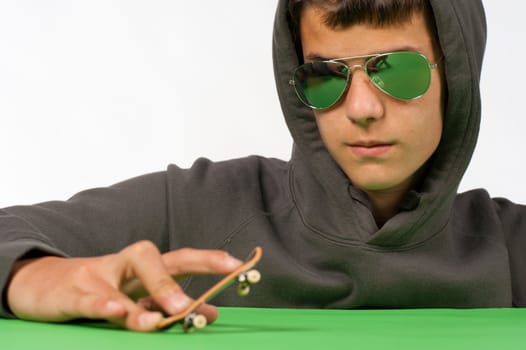 Cool teen posing with a tiny toy skateboard