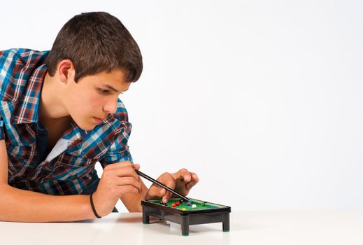 Teenager playing with a miniature snooker table